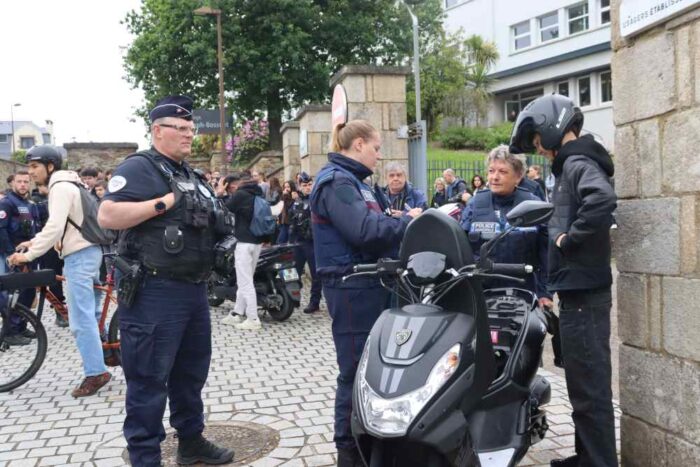 de spoliciers contrôlent un conducteur de scooter devant un lycée, au moment de la sortie des cours
