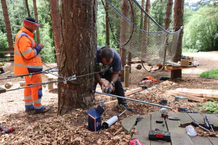 deux techniciens travaillent à mettre de nouvelles fixations sur les arbres pour l'acrobranche