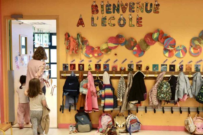 un couloir d'école avec petits porte-manteaux et une banderole Bienvenue à l'école